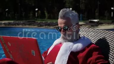圣诞老人在游泳池里放松，用手提电脑开疯狂的玩笑